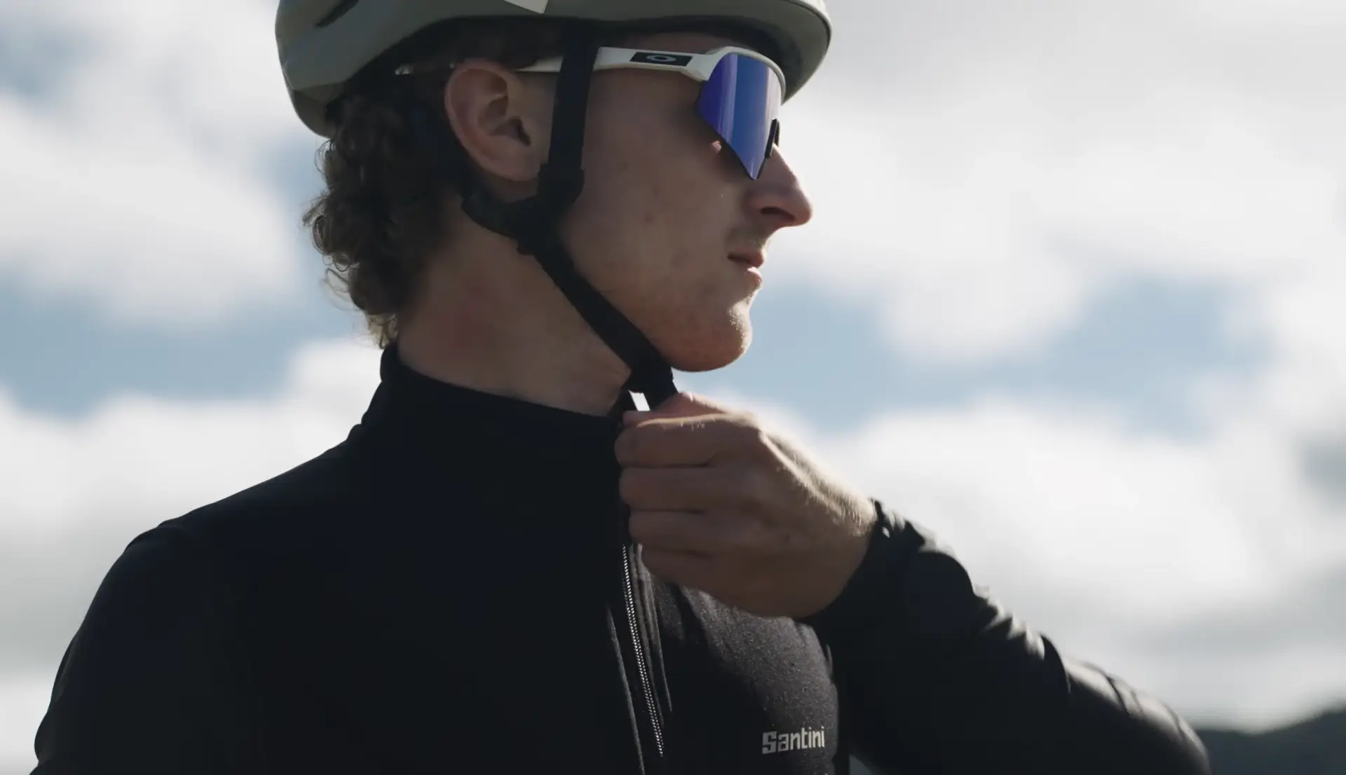 jeune cycliste entrain de fermer sa veste, on le sent déterminé, l'image est en légère contre plongée elle a un rendu professionnel