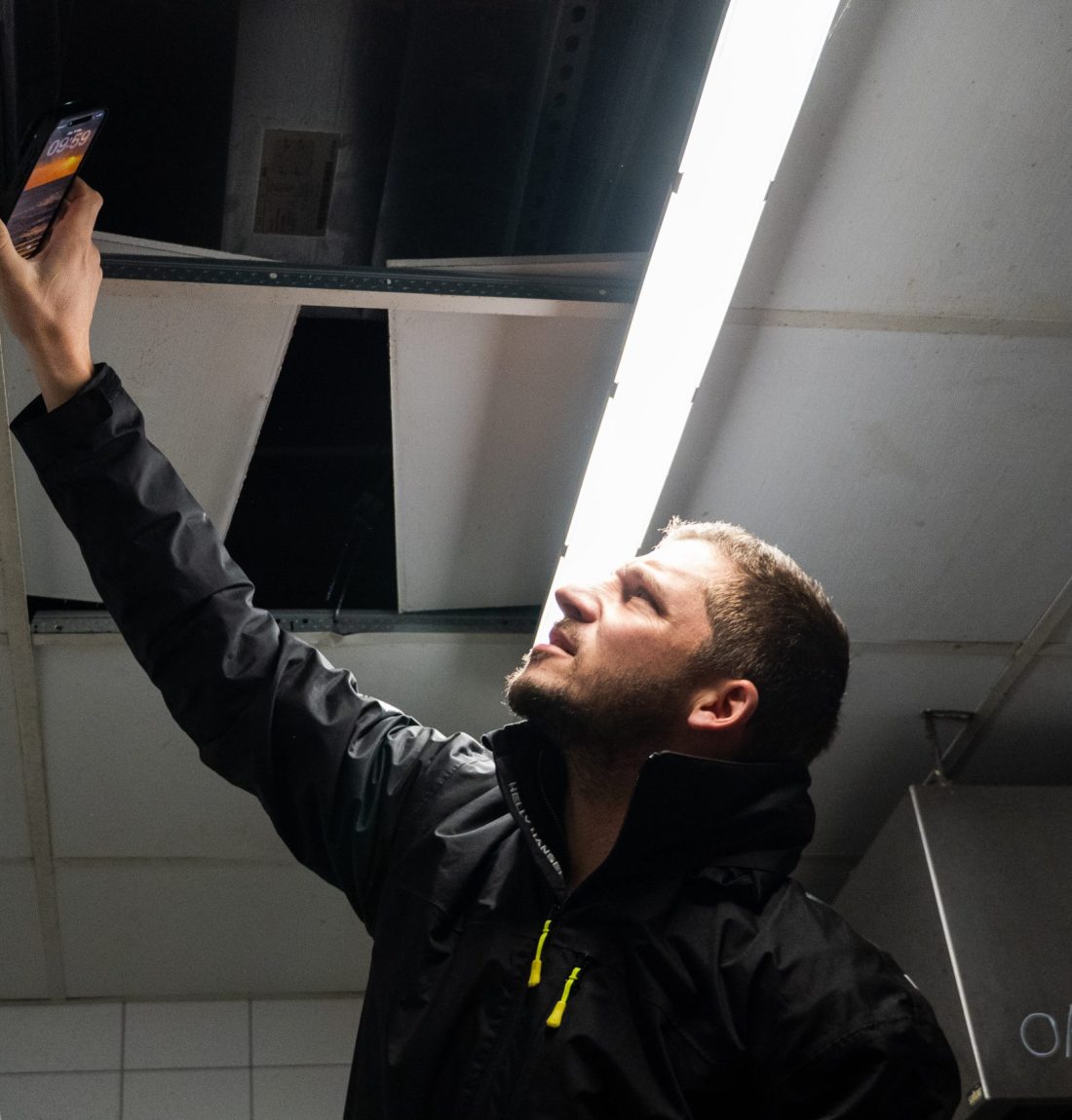 Ludovic de LP-Ventil expertise le plafond pour une ventilation de restauration pour un restaurant. Il s'aide de son téléphone pour éclairer dans le faux-plafond.