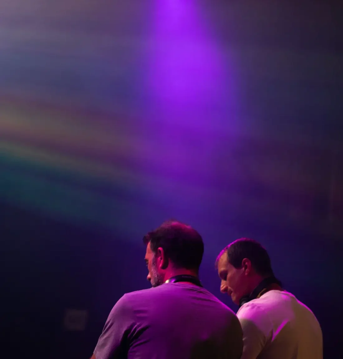Le groupe The Deep Brothers mixe en concert, ils sont de dos et une lumière violette est focalisé sur eux.
