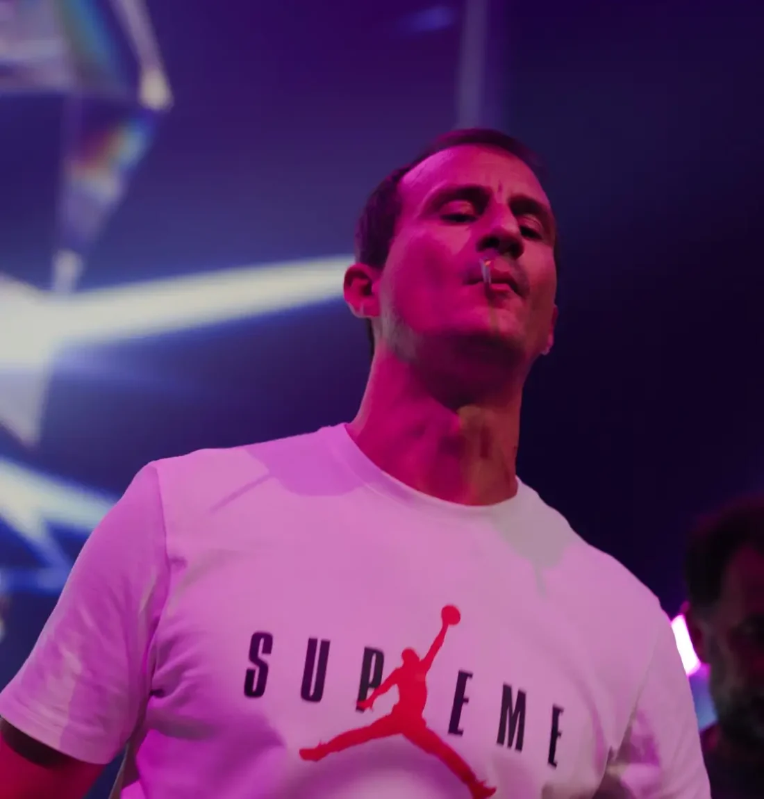 Un des deux membres du groupe The Deep Brothers porte un tee shirt supreme, il fume cigarette il est devant l'écran géant derrière la scène.