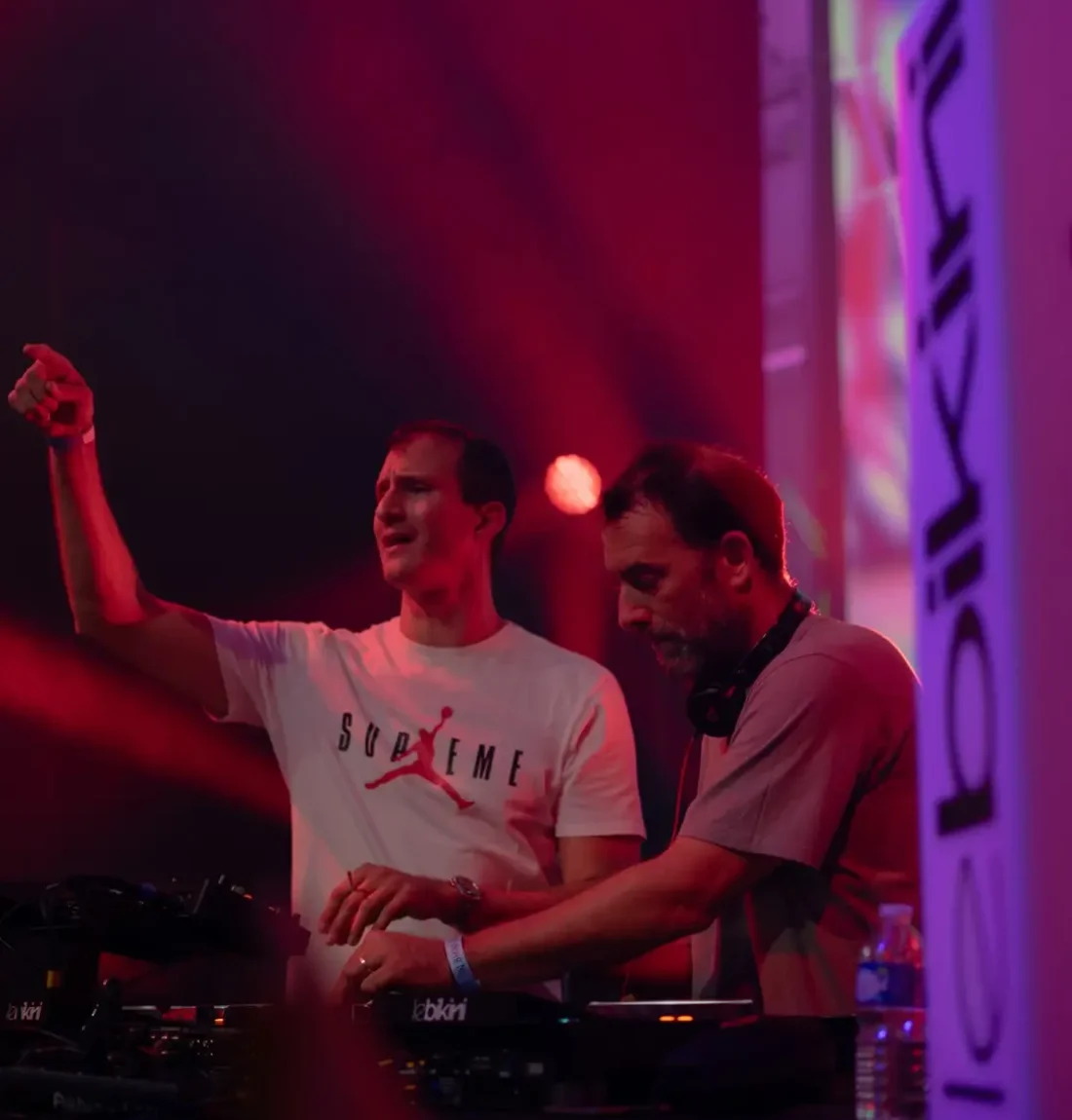 The Deep brothers sont entrain de mixer l'un danse et l'autre est aux platines; Le logo de la salle de concert le bikini est en premier plan.