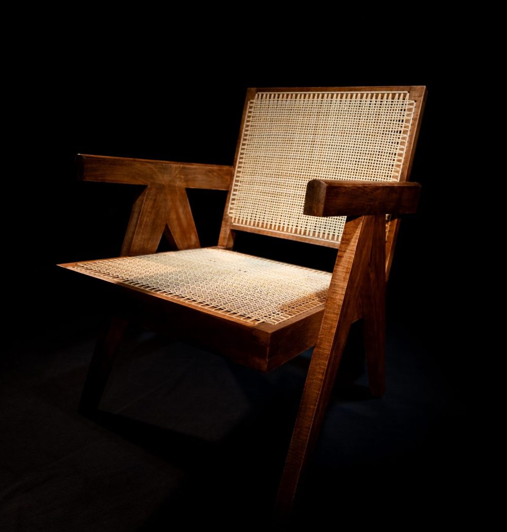 chaise de créateur sur fond noir éclairé en top shot, image contrastée par le biais des matériaux et de la lumière