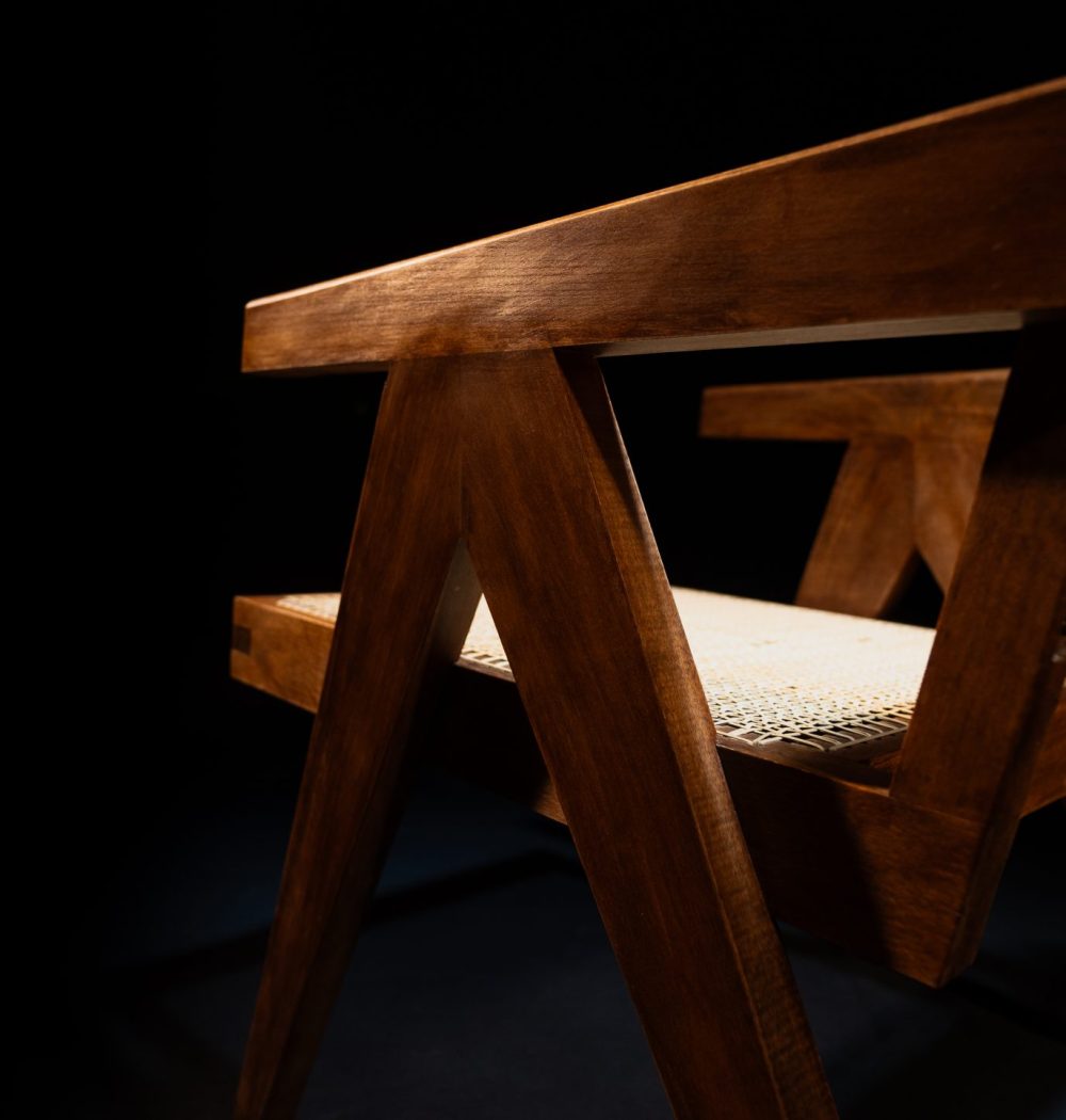 Chaise en bois exotique avec une assise en cannage chaise design de créateur mise en valeur par un fond noir et un éclairage professionnel.