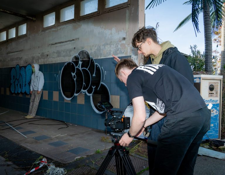 Le rappeur est dans un box de nettoyage entrain de poser, pendant ace temps, on voit l’équipe technique entrain de cadrer à l’aide d’une caméra Sony posée sur un trépied professionnel Manfrotto, le box de nettoyage est tagué, sale, il parait abandonné